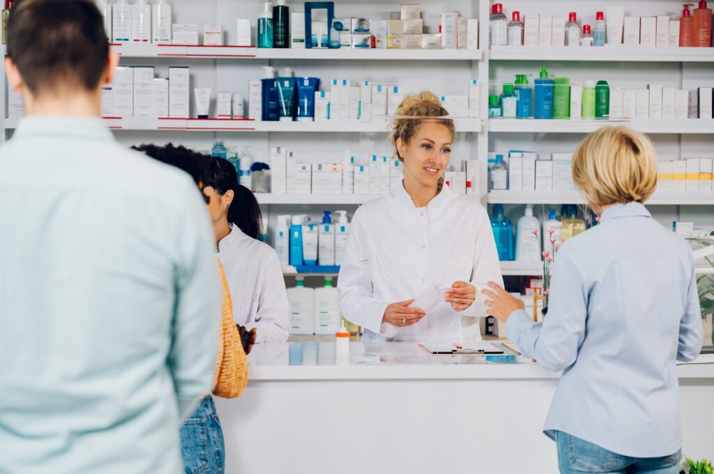 Pharmacist handing a filled prescription to a patient at the pickup counter