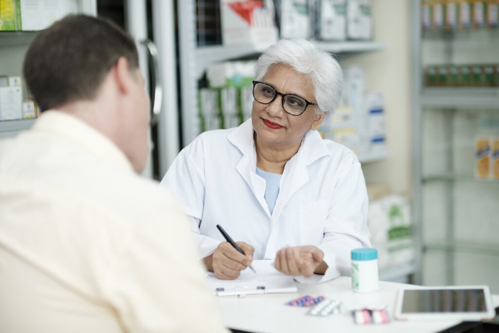 Smiling pharmacist talking with a patient at the pharmacy counter