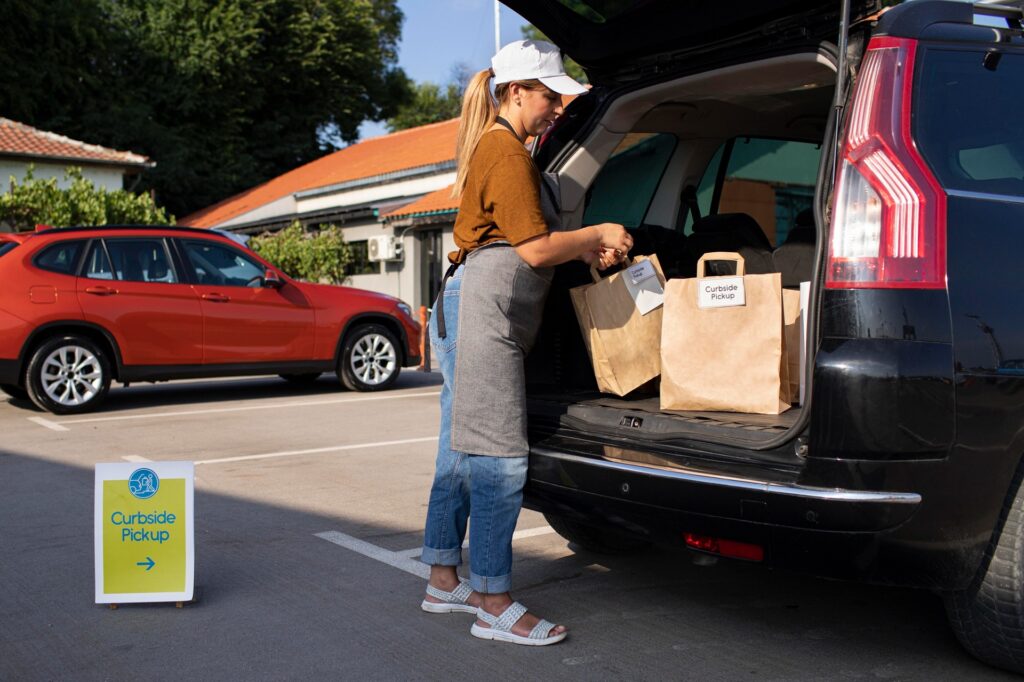 Team member loading curbside pickup orders into a customer's vehicle outside Faith & Healing Pharmacy