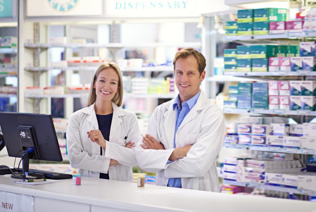 Two pharmacists standing together behind the dispensary counter